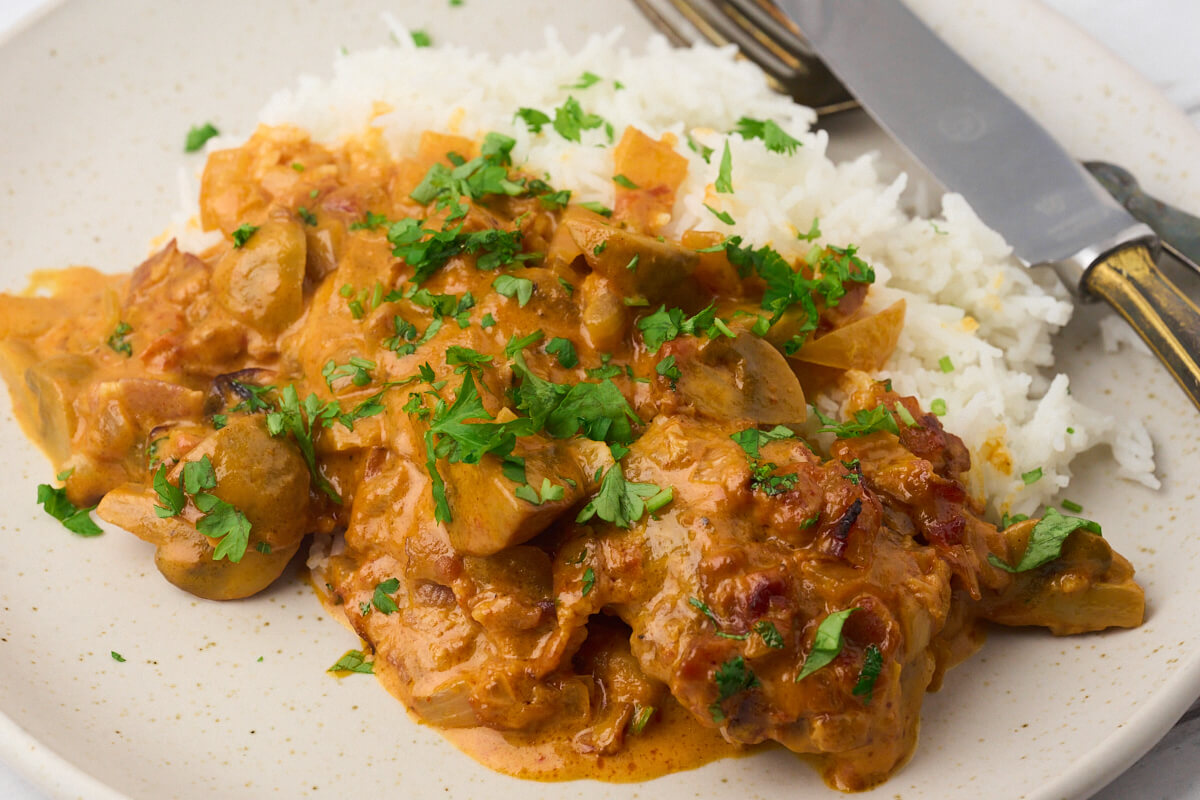 plate with a serving of rice with pork tenderloin in mushroom sauce.